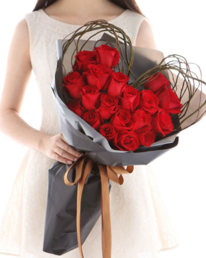 Medium bouquet of 19 red roses that features a heart-shaped wreath wrapped in matte paper