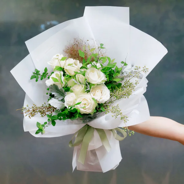 Medium bouquet of 9 white roses and seasonal green flowers wrapped in quality matte paper