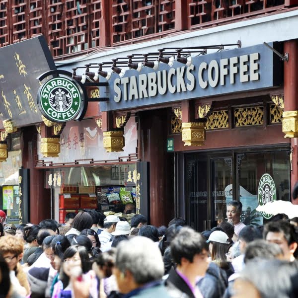 Pedestrians make their way past a Starbucks China in Shanghai street.